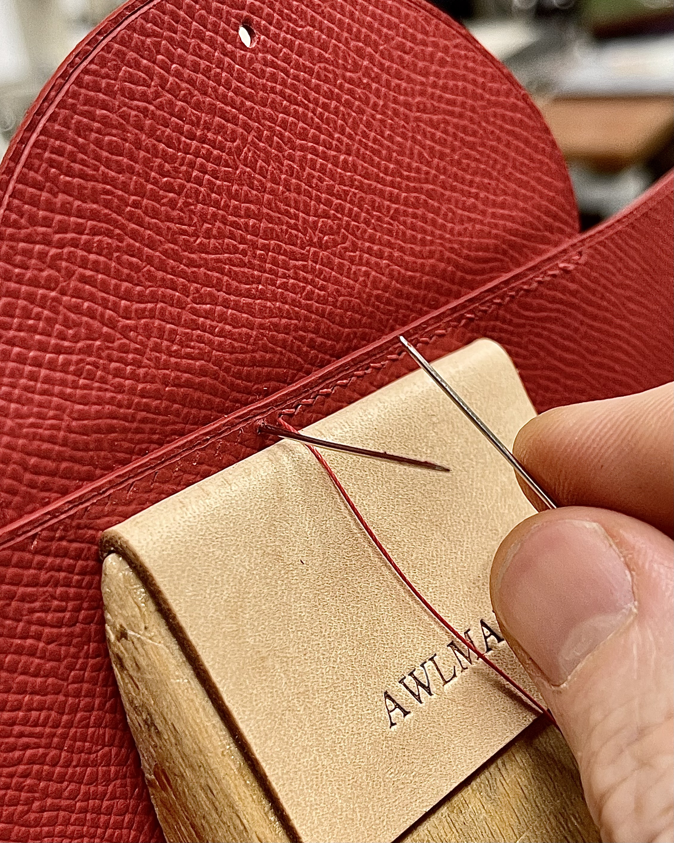 Hand stitching red leather at the Awlmark atelier